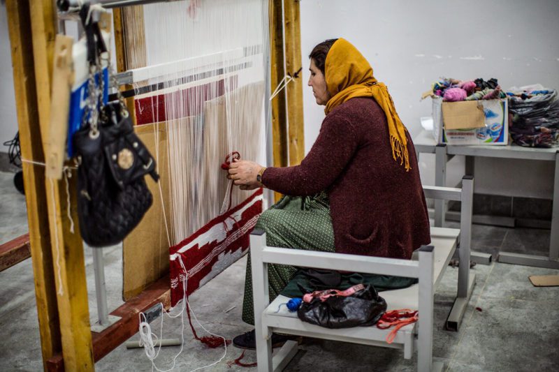 Woman working loom at Yezidi Rug Factory