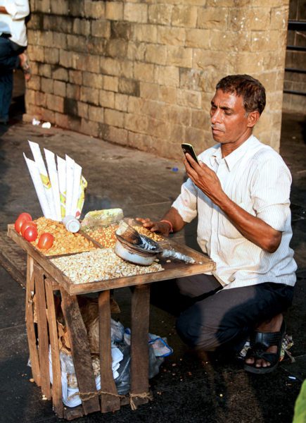 Indian man at simple desk looking at cell