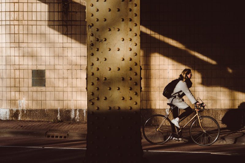 Woman pedaling bike next to pillar