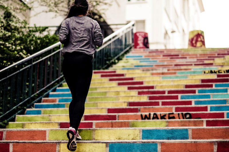 Woman running up colorful stairs