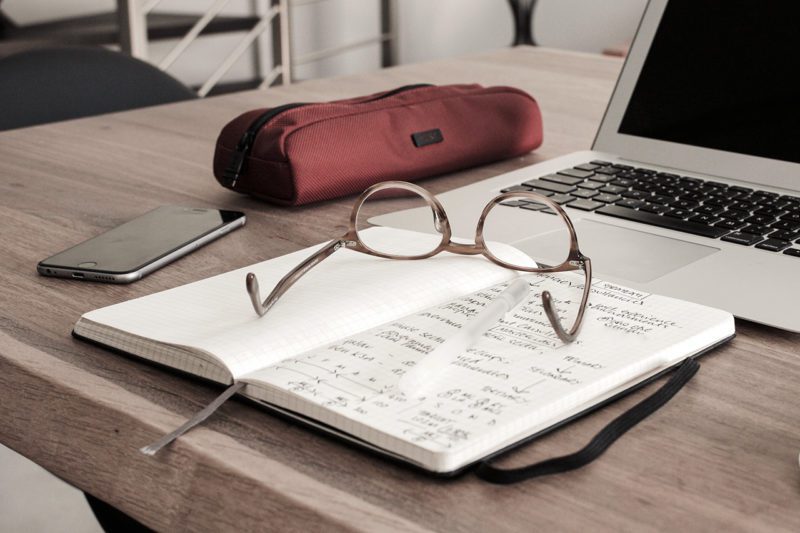 Glasses on notebook next to computer