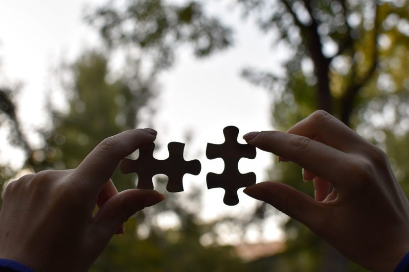Two jigsaw puzzle pieces in hands