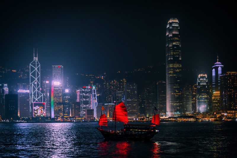 Ship with red sails in Asian harbor