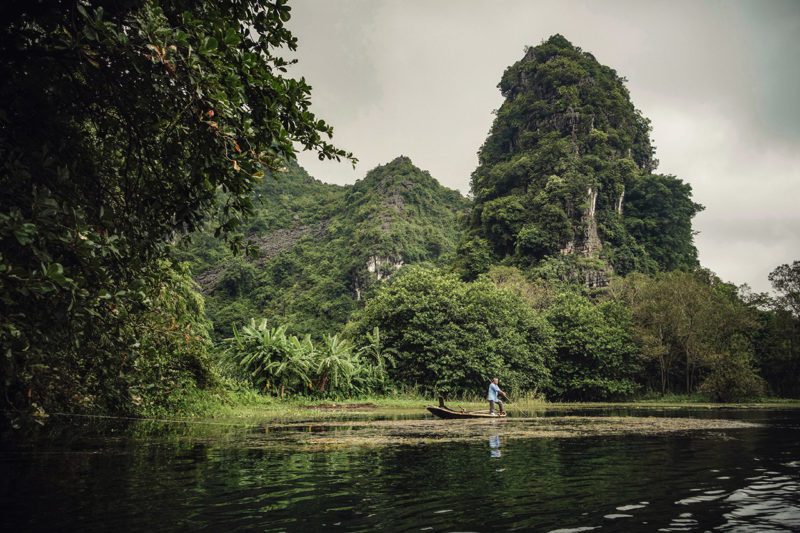 Man steering boat in river among forest