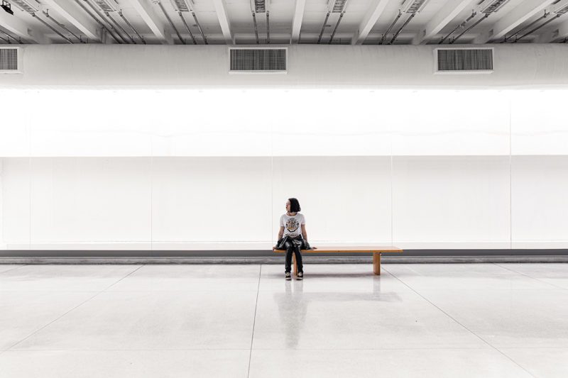 Asian woman sitting alone in large white room
