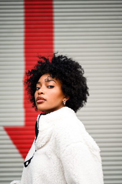 Black woman in front of downward red arrow on wall