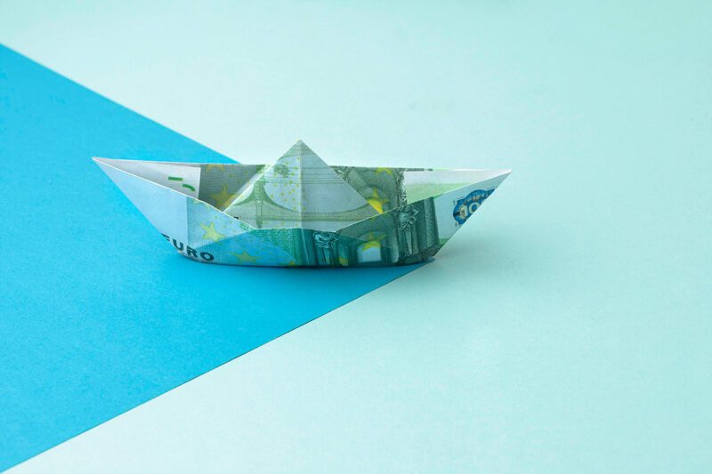 Boat made of money on blue background