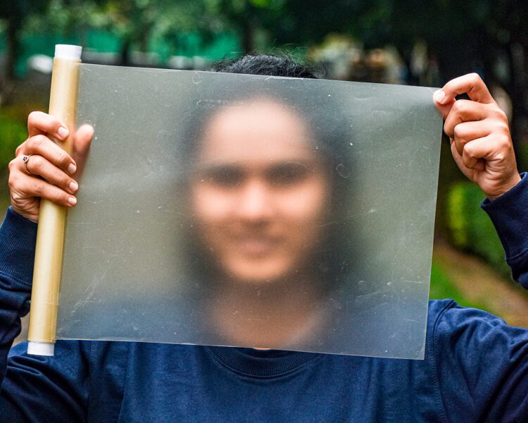 Man holding biodegradable plastic sheet in front of face.