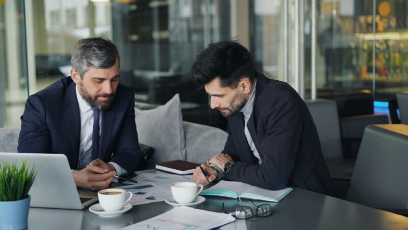 Two business men in suits meet in office
